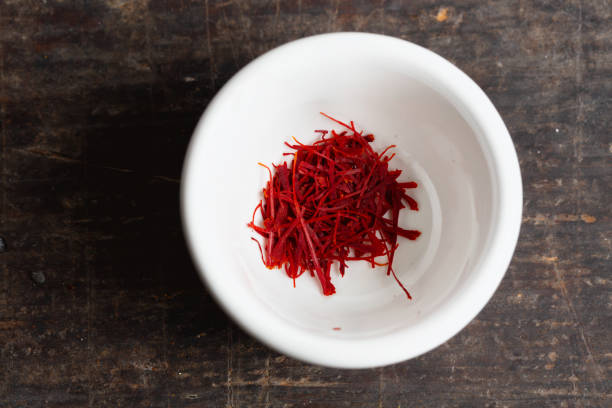 saffron in a small white bowl on rustic wooden background,
